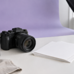 Camera and blank photo paper in a lavender-toned studio